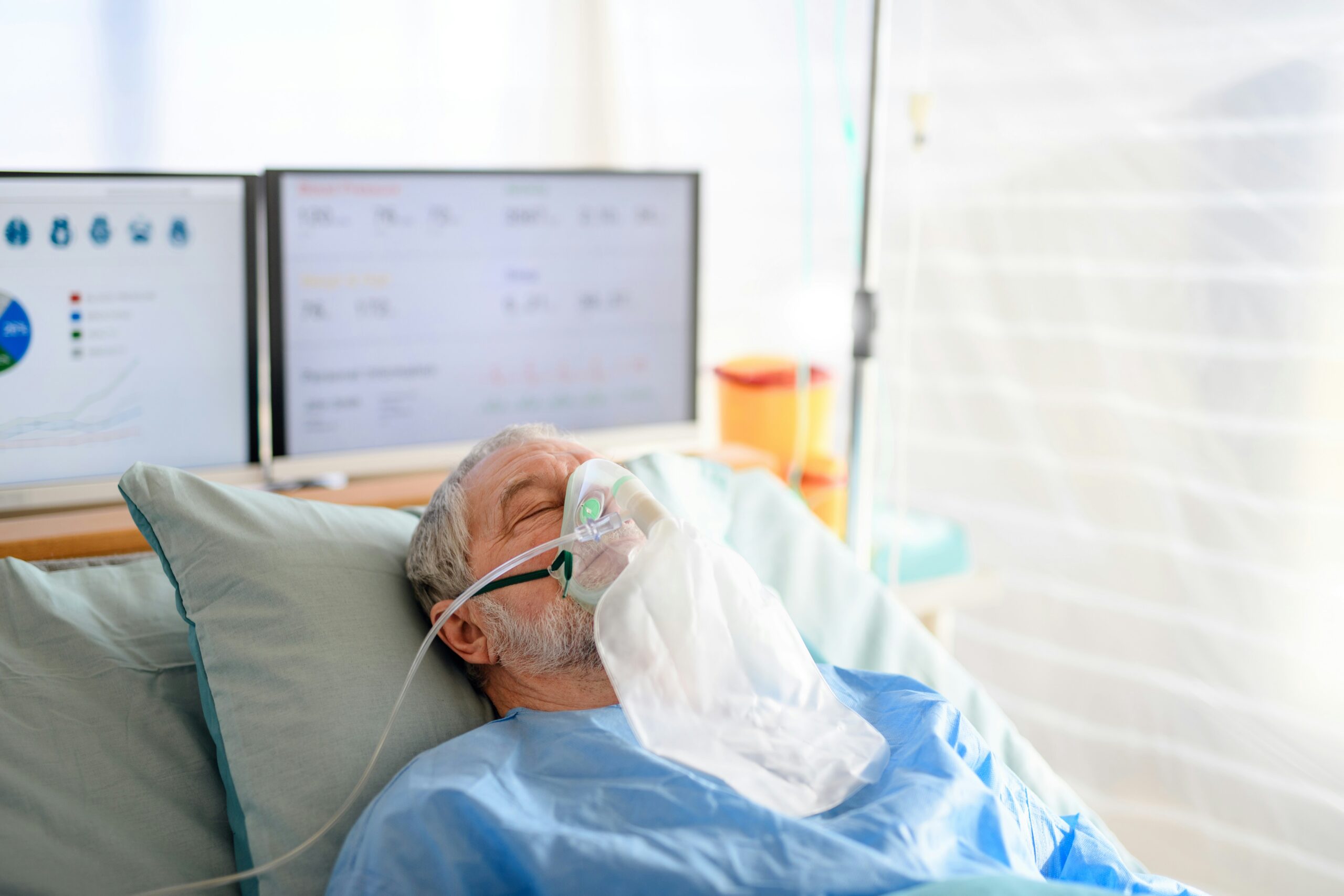 a man lying on a hospital bed with a respirator